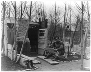 Fig. 31. A squatter named Blackie in Chicago, reading a newspaper outside his hut, which is made entirely from driftwood and stones, and surrounded by sparse trees. A small sign on the right reads “Sleepy Hollow.”