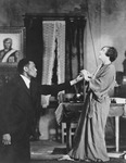 Black and white production photo of Paul Robeson and Mary Blair in the final scene from All God’s Chillun Got Wings in 1924. Robeson is shown kneeling and reaching out his hand to Blair, who holds his hand.
