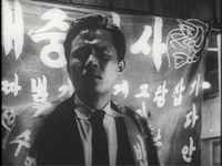 Protagonist Cheolho lingers in turmoil before a noren covered in white calligraphy of a yatai food stall.
