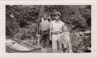 A black-and-white photograph of Joe Seliga and his family next to a canoe on the shore.