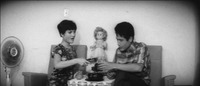 A black-­and-­white shot from Dangerous Youth showing a woman and a man sitting in a living room drinking soda.