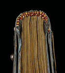 A hard bound book. The top of the book, the threads on its spine, and the ornament on its cover, are seen.