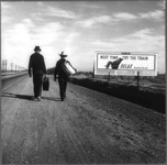 Fig. 39. A photo shows two men, from behind, walking along a dirt road near a large billboard picturing a man leaning back in a reclining chair; it says “Next time, try the train. Relax.”