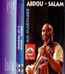 One of the previously shown album covers for the music group Abdou Salam and Les Tendistes. The cover portrays a man, presumably the leader of the group, looking into the camera as he plays an instrument in front of a black background. The album title and track listing are written sideways in a non-­English language on the left side of the cover. A small but prominent condom advertisement sits in the middle of the cover.