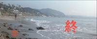 Red titles calligraphy at the bottom right reading "The End" is superimposed on a beachfront in profile, dominated by the sea in the center and right side, with mountains and a pedestrian walking in the background forward on the left side.