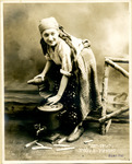 Black-and-white photograph of actress Sonia Alomis as a Russian maiden repairing a pair of boots.