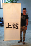 Zhao Liang holds up a scroll painting with the words Petition. It is the title calligraphy for his film by that name. It was brushed by Li Xianting, a powerful critic that threw his support behind Chinese documentary directors. It is in his Cao Changdi studio in Beijing.