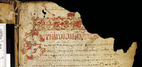 A small portion of a tan parchment with Greek lettering in red. An inscription is on the left side.