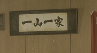 A calligraphic sign hangs on a wooden wall
