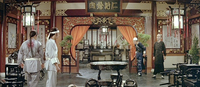 Two pairs of people face each other in a richly decorate room. Calligraphy is visible on the wall scrolls and boards.