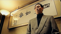 A man stands in front of a wide calligraphic poster.