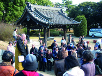 Fig. 12. A photograph of a monk (left) speaking to a group of people gathered on the steps (right) below.