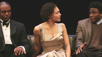 Amelia Workman, as Thomasina, sitting between Desmond (Prentice Onayemi) (left) and Thomas (Douglas Scott Streater) (right) on the couch in Thomas’s living room.