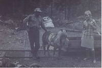 Black and white photograph of Lewis outside small coal mine with miner and the pony he uses to haul the coal from the mine.