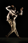 Fig. 1. Male dancer in silver suit, back to camera, arms raised and bent at elbows, left leg stepping to the side in front; he’s on the move.
