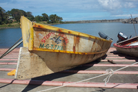 A color photograph of the fishing canoe Storm Petrel tied next to water.