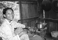 Fig. 70. A Cambodian woman shows off her metal cooking pot atop a portable ceramic cooking stove. The stove is the size and shape of a modern plastic bucket.