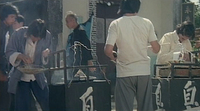 White calligraphy on two black boxes. Says "Smelly''. The man is selling Stinky Tofu on top of it.