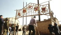 Red calligraphy characters are set in a frame of a film studio gate.
