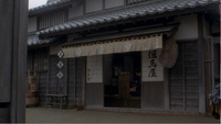 A building has a banners and placards with white and black calligraphy, with white calligraphy superimposed over it.