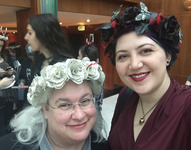 A selfie of two people smiling into the camera, wearing handmade flower crowns. The crown on the left has flowers made from book pages, and the one on the right is black and red with butterflies.