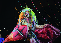 Performer Taylor Mac singing in giant butterfly wings, a breastplate, and a plastic rainbow wig during a performance of A 24-­Decade History of Popular Music in San Francisco, California.