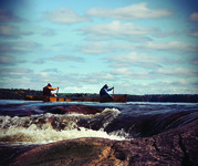Canoeists paddling a Wenonah Kevlar canoe above a rapids in the Boundary Waters Canoe Area.
