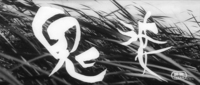 Blades of grass have white title calligraphy superimposed over them, in black and white cinematography.