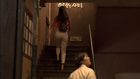 A woman walks up a flight of stairs with white calligraphy printed on the wall.