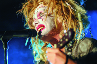 Performer Taylor Mac wearing white makeup with glitter and sequins and a messy blond wig.