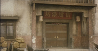 A red board with calligraphy over the doorway of a building.