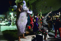 Pedestrian Río Piedras walkway, six movers and musicians send off 2015. Rodríguez Lora removes sparkly gown; others throw glitter into air.