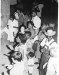 Carole (Gross) Colca (center, looking at camera), along with local residents and children and other civil rights workers, clapping and singing Freedom Songs during the Mississippi Freedom Summer.