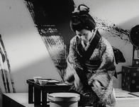 A young woman prepares dinner before a massive brush stroke.