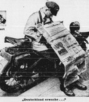 A man selling newspapers dozing on a motorbike.
