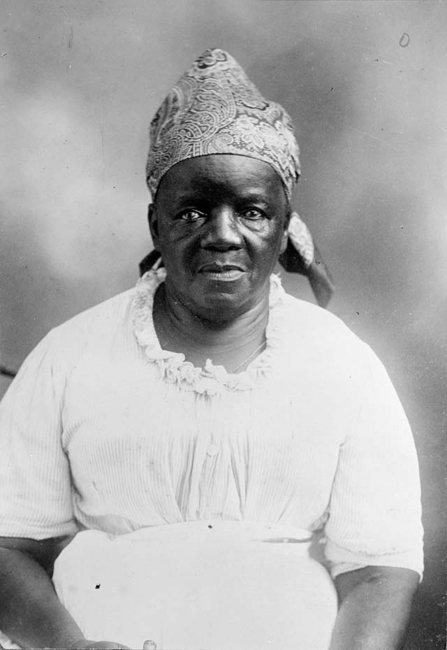 This woman wears a patterned headcloth, a practical garment with links to African and slave clothing styles.